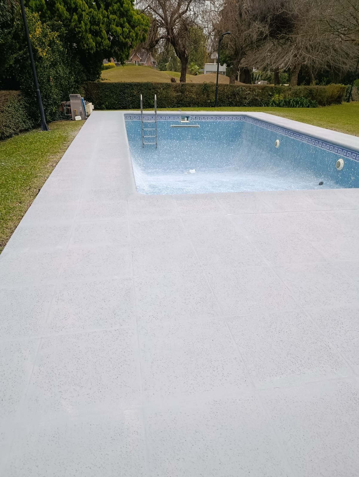 Piscina de hormigón terminada con escalera de acceso, en una vivienda particular