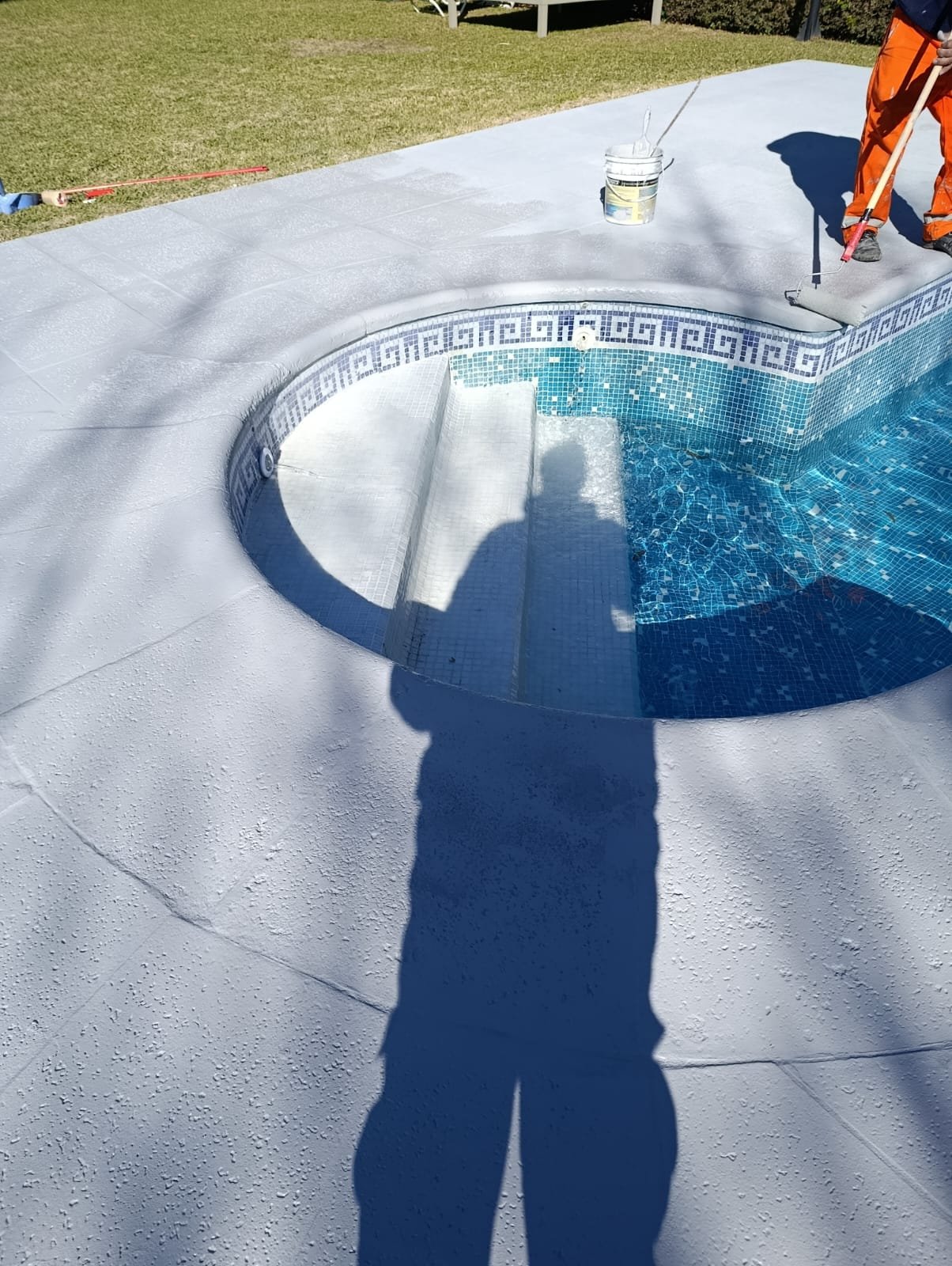 Equipo de Solmat terminando el borde de mosaico de una piscina con agua